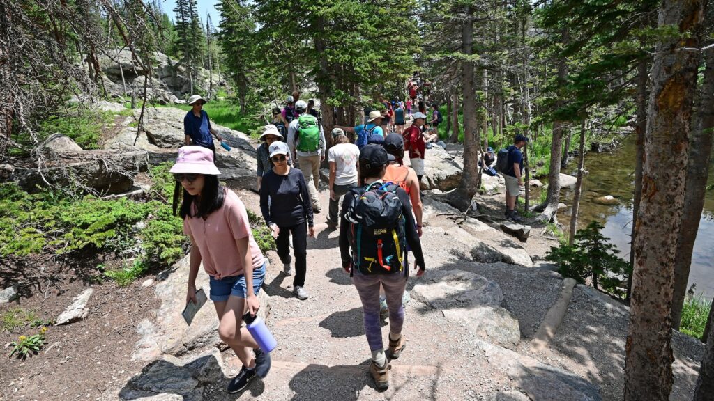 Visitors hike on the crowded Emerald Lake Trail on a sunny summer morning.