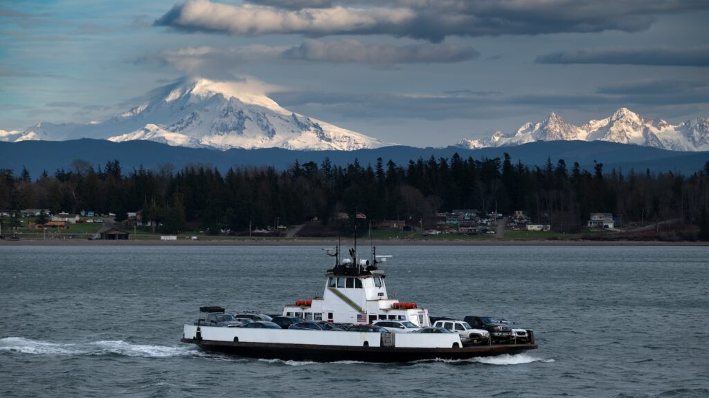 Ferryboat crossing Hale Pass from the mainland to Lummi Island, Washington. Snow covered Mt. Baker and the Three Sisters mountains, in the Cascade Range, can be seen in the background.