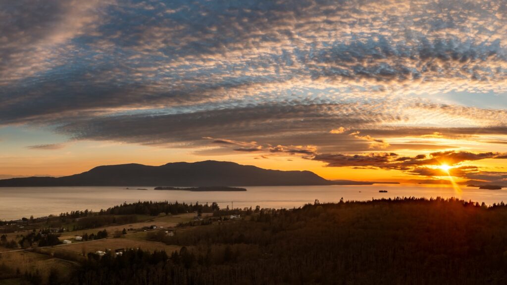 Panoramic sunset aerial view of Orcas Island seen from Lummi Island, Washington. Looking across Rosario Strait towards the San Juan Islands with a dramatic sunset sky over Orcas Island.