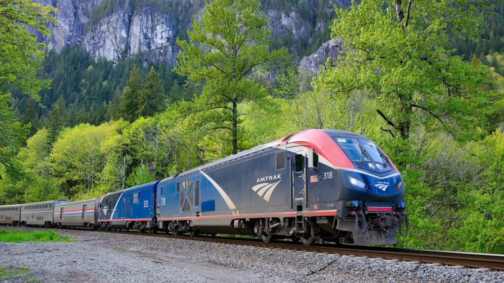 Amtrak Empire Builder passenger train in Cascade Mountain Range with green trees
